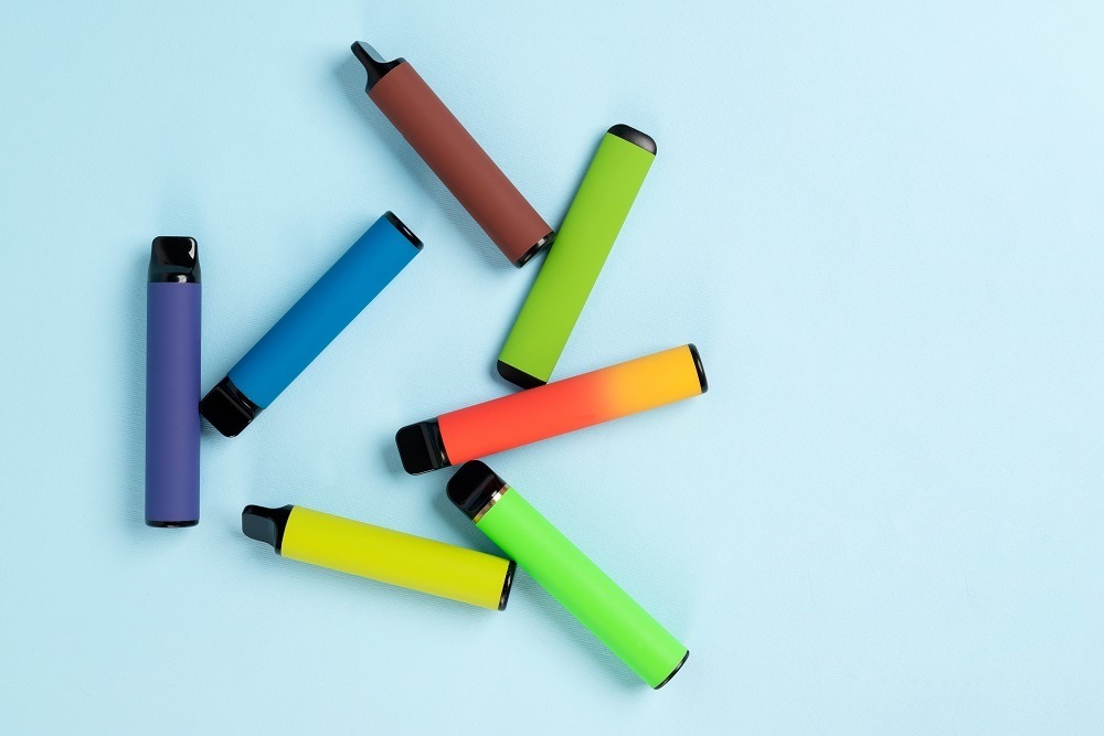 Layout Of Colorful Disposable Electronic Cigarettes With Shadows On A Blue Background. The Concept Of Modern Smoking, Vaping And Nicotine. Top View